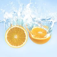 Splash of falling in water fresh orange halves, blue background